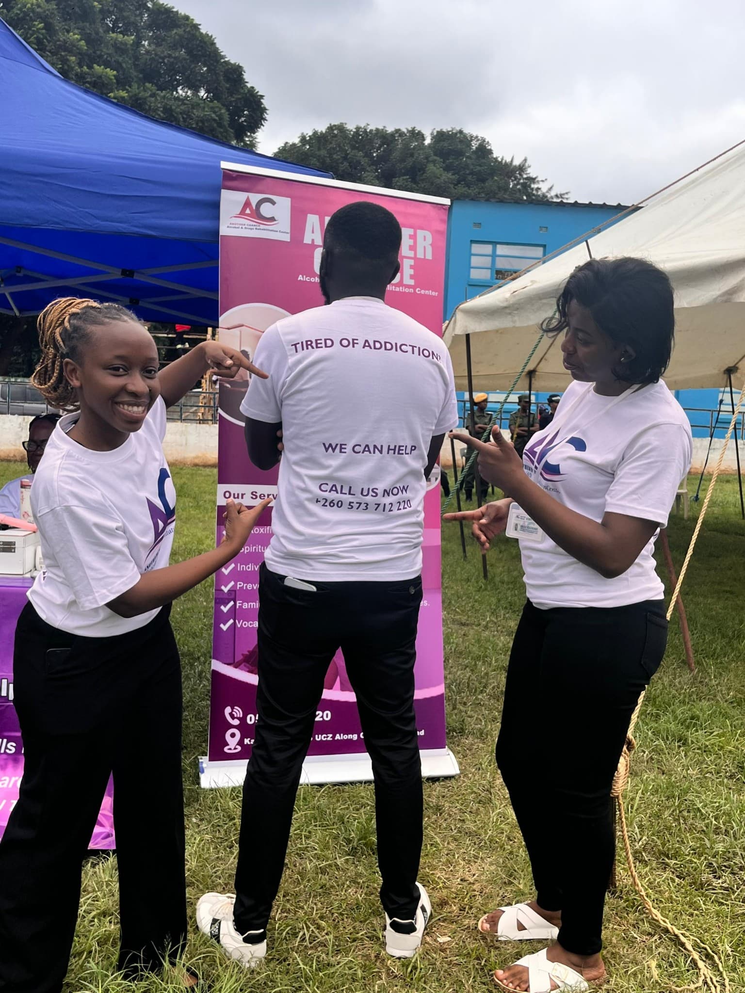 Team members highlighting a recovery support message printed on a shirt at an event